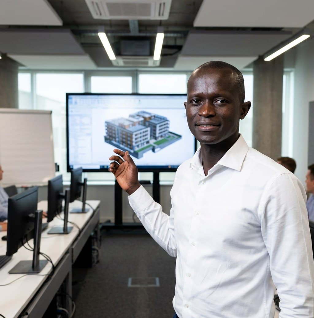 Formateur présentant une maquette numérique de bâtiment devant un groupe, en salle de formation